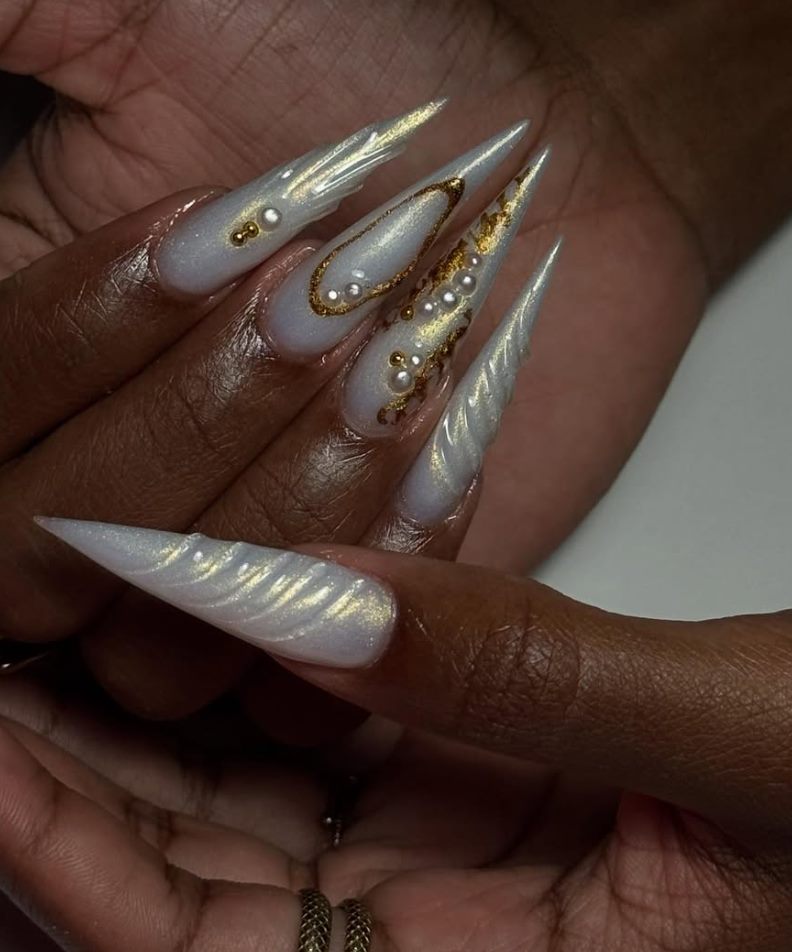 Pose d'ongles stiletto blanc nacré rehaussée de feuille d'or, réalisée par NUA NAILS Tech aux Abymes
